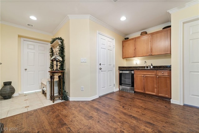 kitchen with crown molding, visible vents, beverage cooler, baseboards, and dark wood-style floors