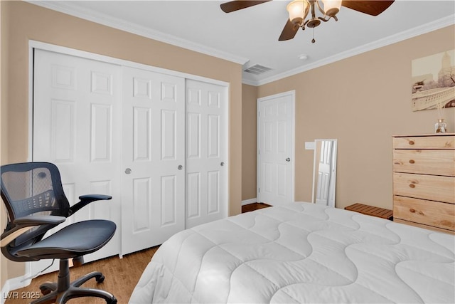 bedroom with a closet, ornamental molding, a ceiling fan, visible vents, and wood finished floors