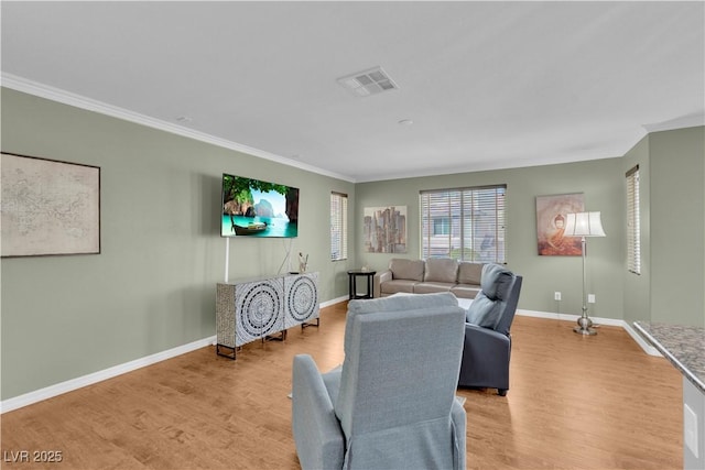 living room with visible vents, baseboards, light wood-style floors, and ornamental molding