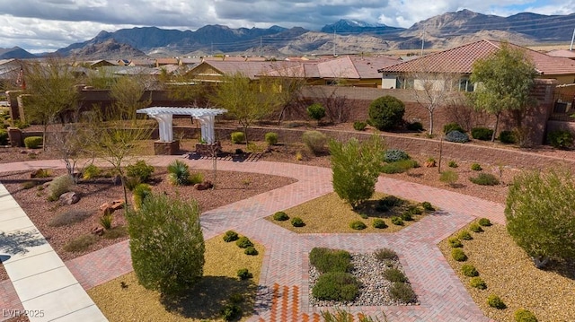 view of property's community featuring a mountain view, curved driveway, and a pergola