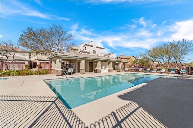 community pool with a patio area and fence