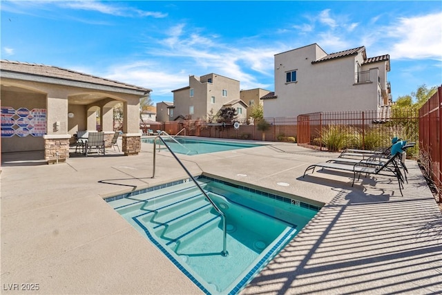 community pool featuring a patio area, a residential view, fence, and a hot tub