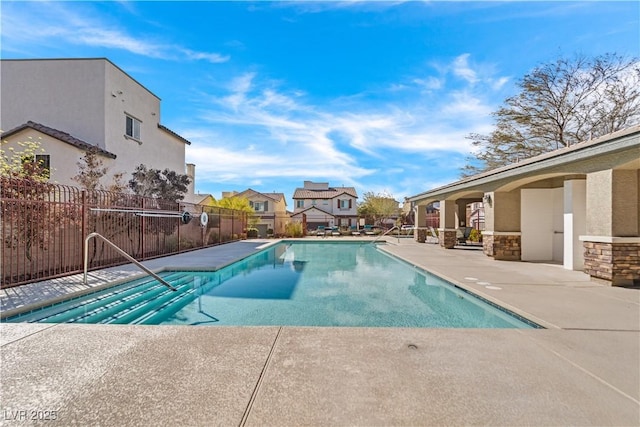 community pool featuring a patio area, fence, and a residential view