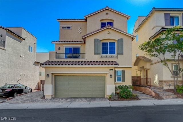 mediterranean / spanish-style house featuring a tiled roof, a garage, a balcony, stucco siding, and decorative driveway