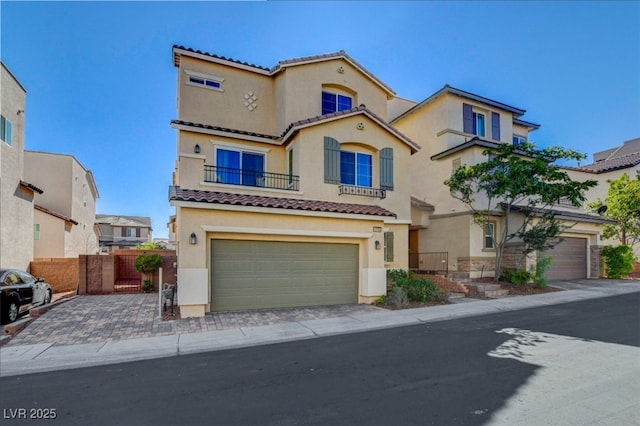 mediterranean / spanish house featuring stucco siding, driveway, an attached garage, a tile roof, and fence