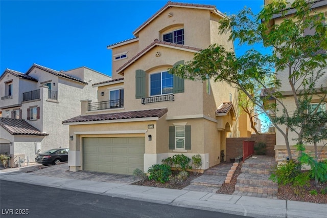 mediterranean / spanish-style home with a garage, driveway, stucco siding, and a tile roof