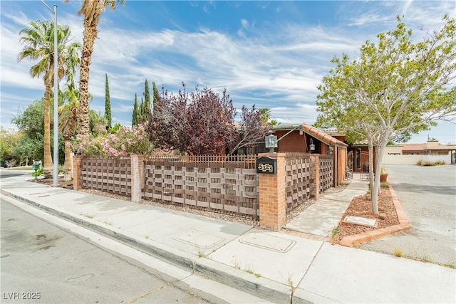 obstructed view of property featuring a fenced front yard, a tile roof, stucco siding, an attached garage, and a gate