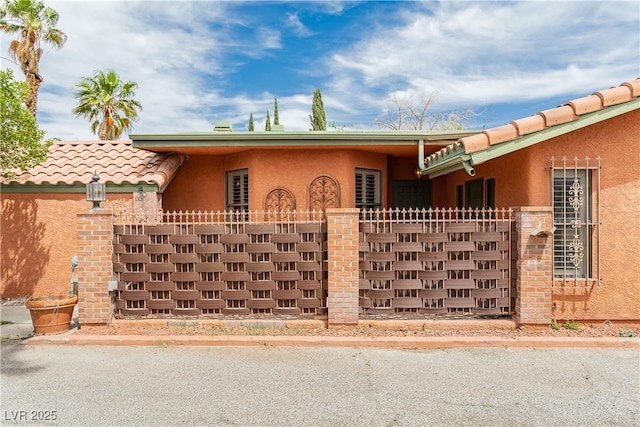 view of front of home with stucco siding, fence, and a tiled roof