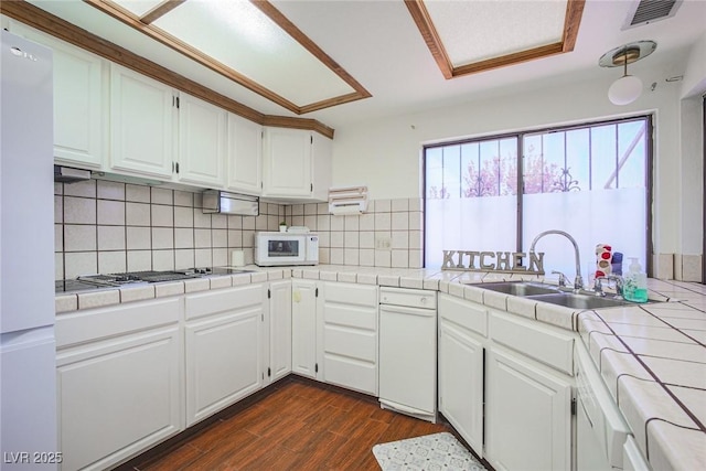 kitchen with visible vents, tile countertops, white microwave, stainless steel gas stovetop, and white cabinetry