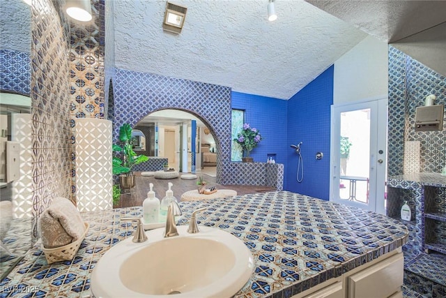 bedroom with lofted ceiling, a textured ceiling, and a sink