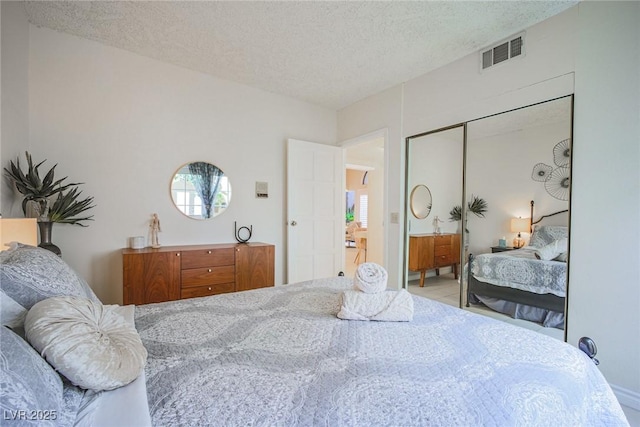 bedroom with a closet, visible vents, and a textured ceiling