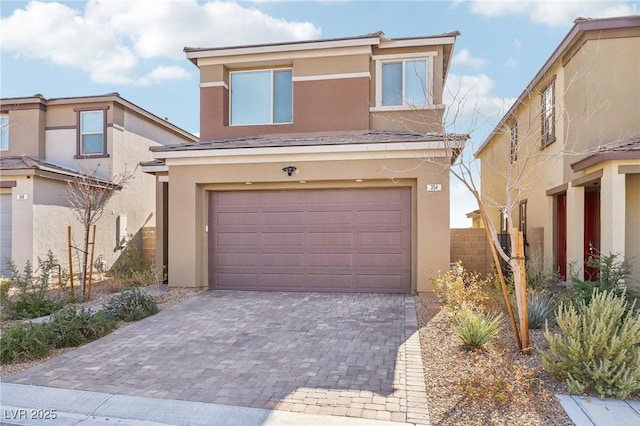 view of front of property featuring an attached garage, fence, decorative driveway, and stucco siding