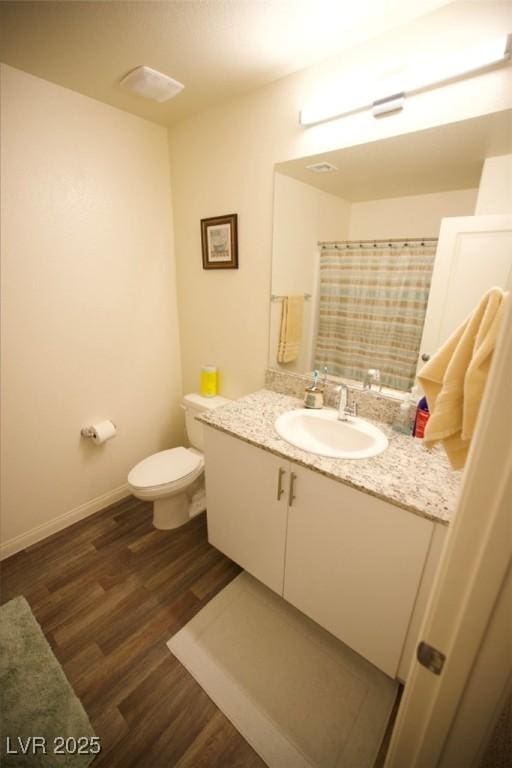 full bath featuring baseboards, a shower with shower curtain, toilet, wood finished floors, and vanity