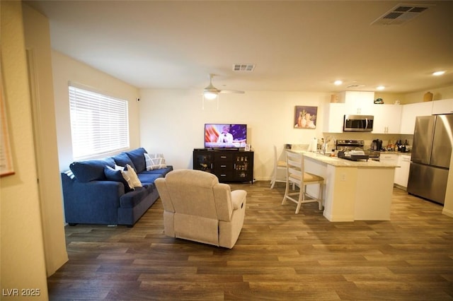 living room featuring dark wood-type flooring, visible vents, and ceiling fan