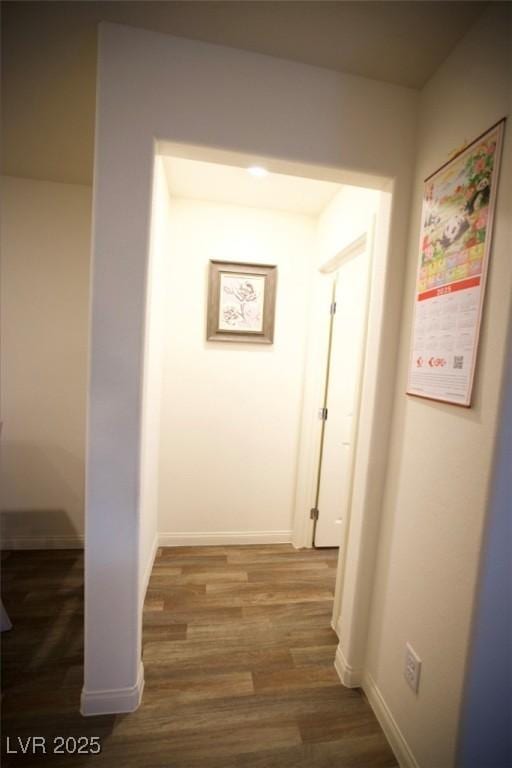 hallway featuring baseboards and dark wood-style flooring