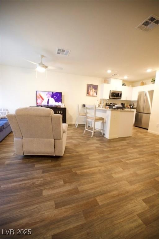 living area with dark wood-style floors, visible vents, and ceiling fan