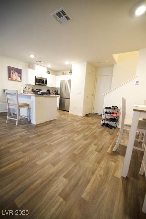 kitchen featuring a peninsula, visible vents, white cabinets, appliances with stainless steel finishes, and light wood finished floors