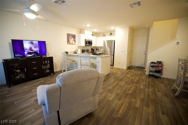 living room featuring dark wood-style flooring, visible vents, and baseboards