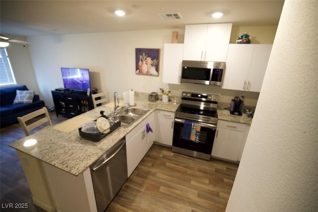 kitchen featuring a peninsula, white cabinetry, stainless steel appliances, and open floor plan