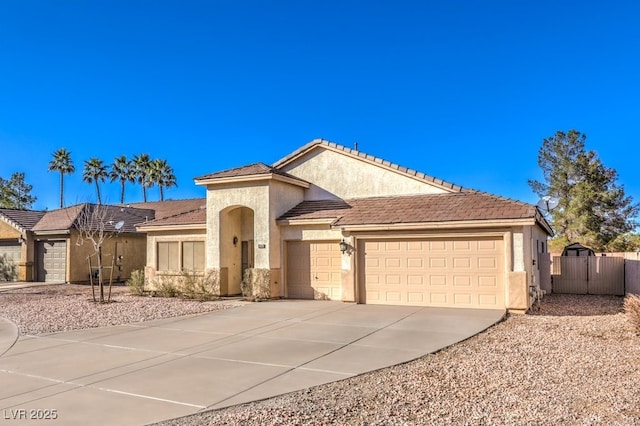 view of front of house with a garage, a tile roof, fence, driveway, and stucco siding