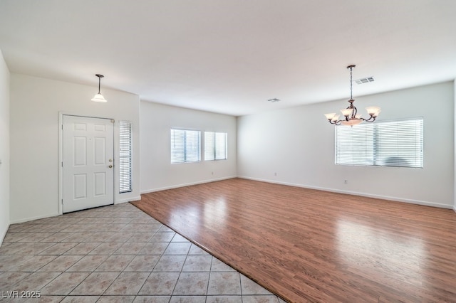 foyer entrance with light tile patterned floors, a chandelier, visible vents, and baseboards