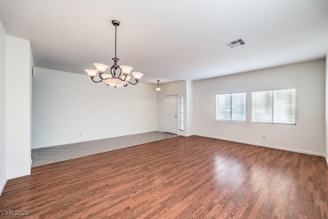 empty room featuring baseboards, visible vents, dark wood finished floors, and a notable chandelier