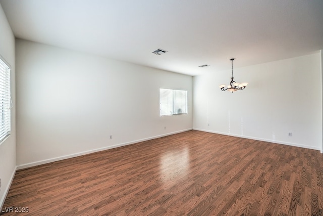 spare room with baseboards, visible vents, dark wood finished floors, and a chandelier