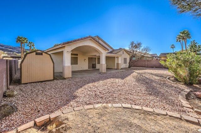 back of property featuring a fenced backyard, an outdoor structure, stucco siding, a shed, and a patio area