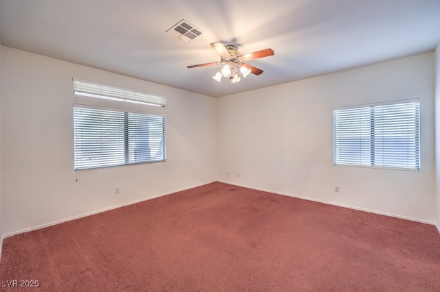 carpeted spare room with visible vents, ceiling fan, and baseboards