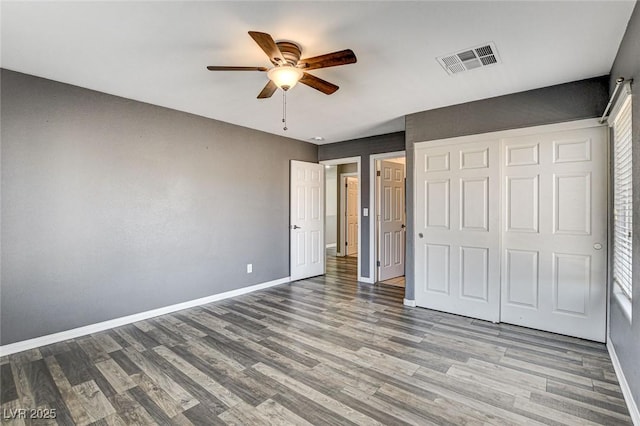 unfurnished bedroom featuring visible vents, ceiling fan, baseboards, and wood finished floors