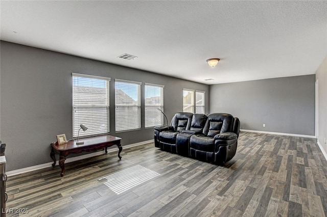 living area with dark wood-style flooring, visible vents, and baseboards