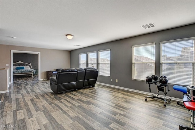 living area with baseboards, visible vents, and wood finished floors