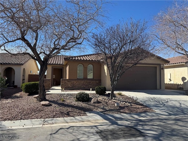 mediterranean / spanish house featuring stone siding, an attached garage, a tiled roof, and stucco siding