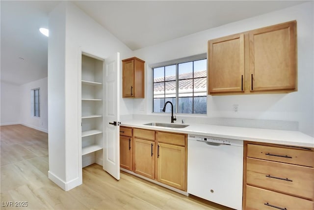 kitchen with light countertops, white dishwasher, a sink, light wood-type flooring, and baseboards