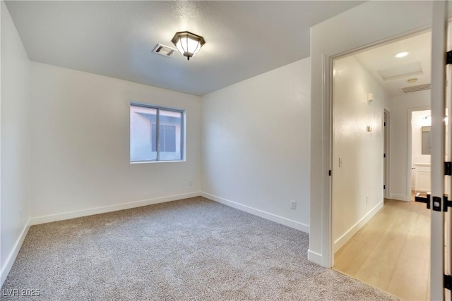 unfurnished room with baseboards, visible vents, and light colored carpet