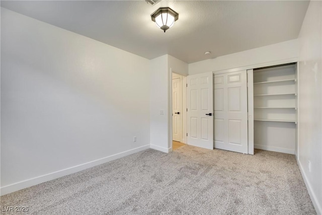 unfurnished bedroom with a closet, light carpet, and baseboards