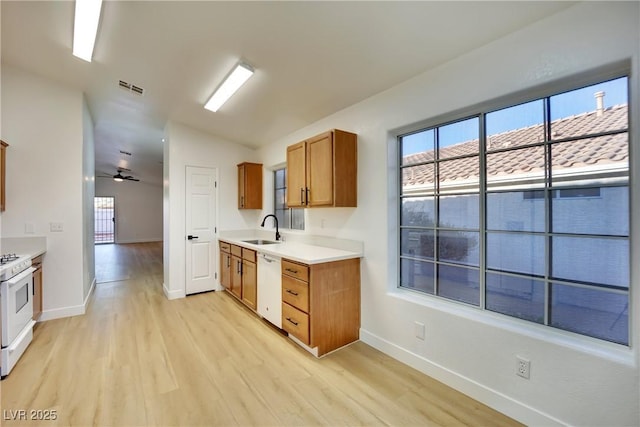 kitchen featuring white appliances, visible vents, brown cabinets, light countertops, and a sink