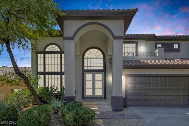 mediterranean / spanish-style home featuring a tile roof, concrete driveway, and stucco siding