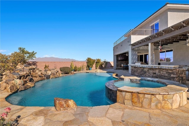 view of swimming pool with a pool with connected hot tub, a patio area, and a mountain view