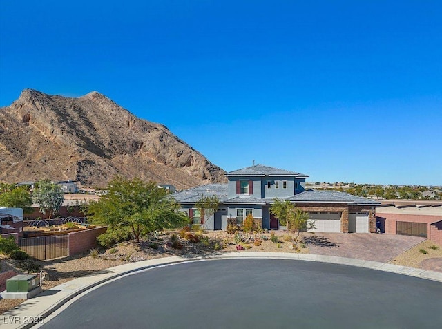 prairie-style home with a garage, decorative driveway, fence, and a mountain view