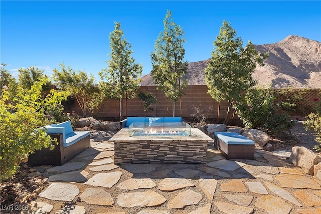 view of patio / terrace with an outdoor fire pit, a mountain view, and a fenced backyard