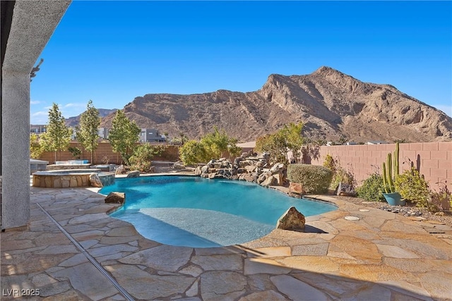 view of swimming pool featuring a pool with connected hot tub, a patio area, a fenced backyard, and a mountain view