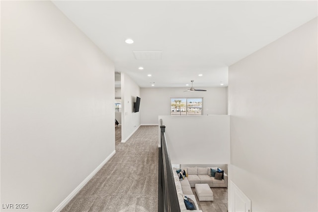 corridor featuring light carpet, recessed lighting, baseboards, and an upstairs landing