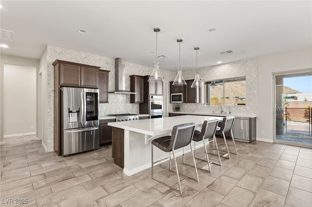 kitchen with light countertops, visible vents, appliances with stainless steel finishes, dark brown cabinets, and wall chimney exhaust hood