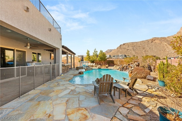 view of pool with ceiling fan, a patio, a mountain view, fence, and a fenced in pool