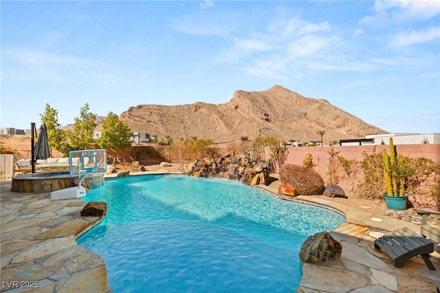 view of pool with a pool with connected hot tub, a fenced backyard, a mountain view, and a patio