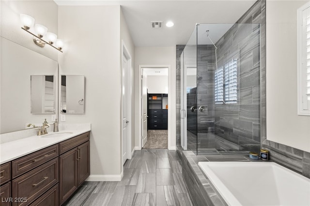 full bath featuring visible vents, a stall shower, vanity, tiled tub, and baseboards