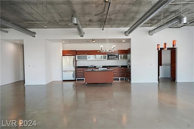 kitchen with a kitchen island with sink, appliances with stainless steel finishes, dark countertops, modern cabinets, and pendant lighting