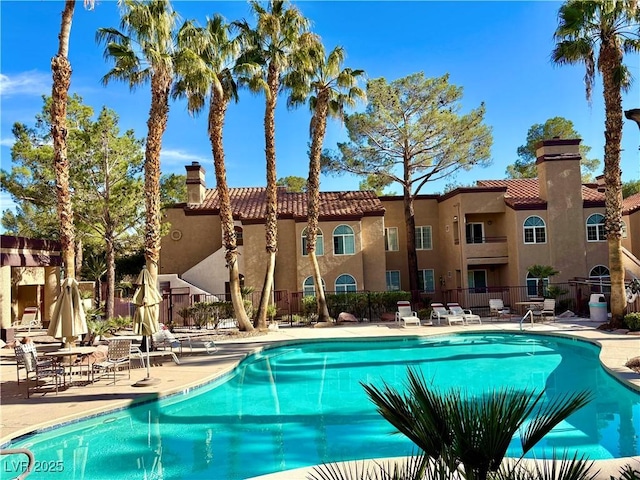 community pool with a patio area and fence