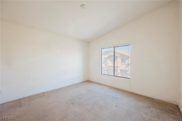 unfurnished room with light colored carpet and vaulted ceiling